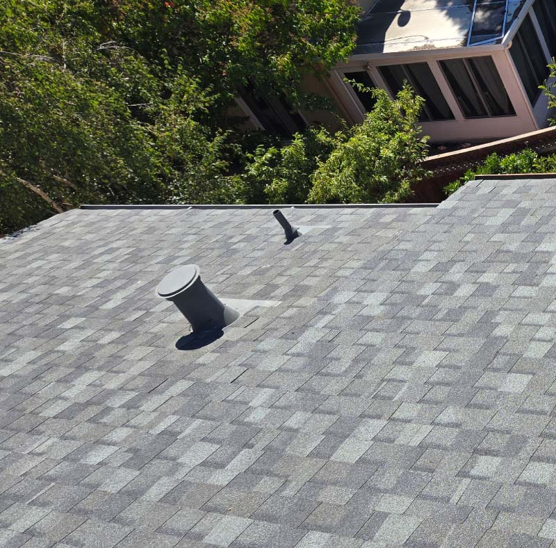Grey asphalt shingle roof with professional aluminum gutter installation and roof ventilation system for a residential home in Oakland CA