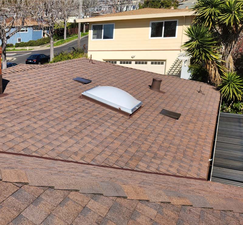 Brown architectural shingle roof replacement featuring a new domed skylight installation and roof ventilation system on a hillside home in Oakland CA.